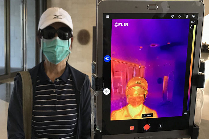 An infrared thermometer is used to check the temperature of guests at a hotel entrance in Yangon, Myanmar.