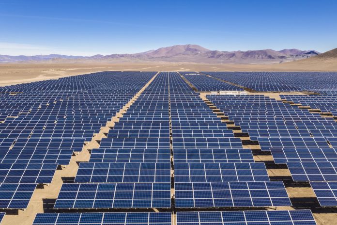 Aerial view of hundreds solar energy modules or panels rows along the dry lands at Atacama Desert, Chile. Huge Photovoltaic PV Plant in the middle of the desert from an aerial drone point of view