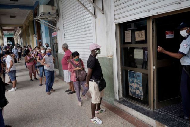 People wait in line to enter a currency exchange office in Havana, Cuba