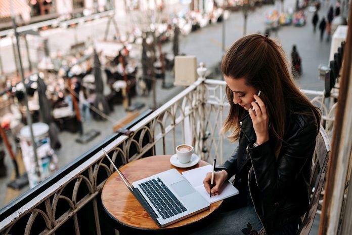 Young female entrepreneur working outdoors. Writting in a notebo