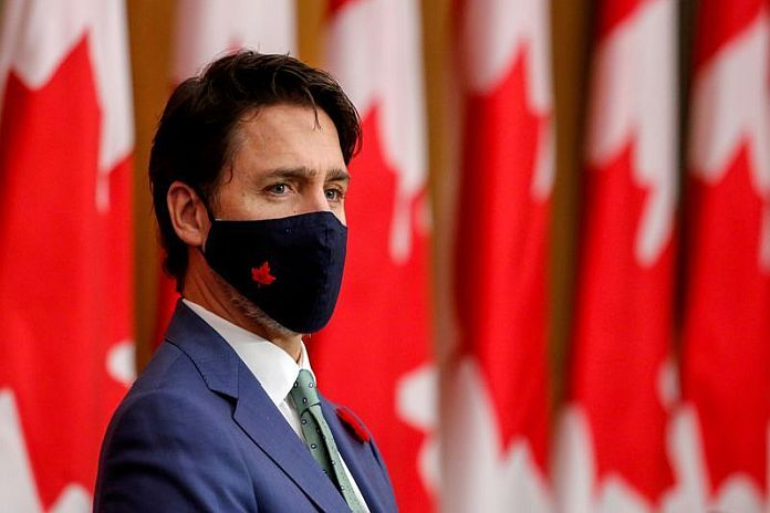 FILE PHOTO: Canadian Prime Minister Justin Trudeau listens while wearing a mask at a news conference in Ottawa