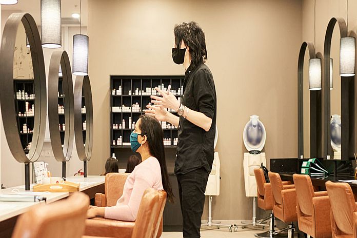 Hairstylist in a face mask talking with a customer in a salon