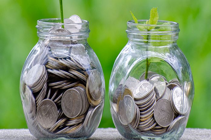 Coin tree Glass Jar Plant growing from coins outside the glass jar on blurred green natural background money saving and investment financial concept